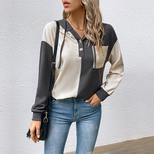 Frau in zweifarbigem Hoodie und Jeans, modisch gekleidet, mit schwarzer Umhängetasche. Trendige Damenmode, lässiger Stil, Herbstoutfit.