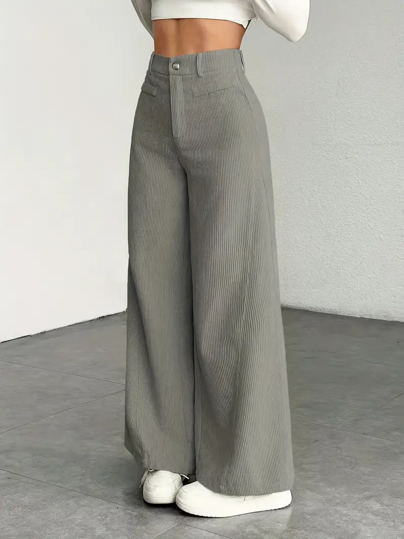 Graue, weit geschnittene Cordhose für Damen, kombiniert mit weißen Sneakern. Modetrend, bequeme Passform, ideal für lässige Outfits.
