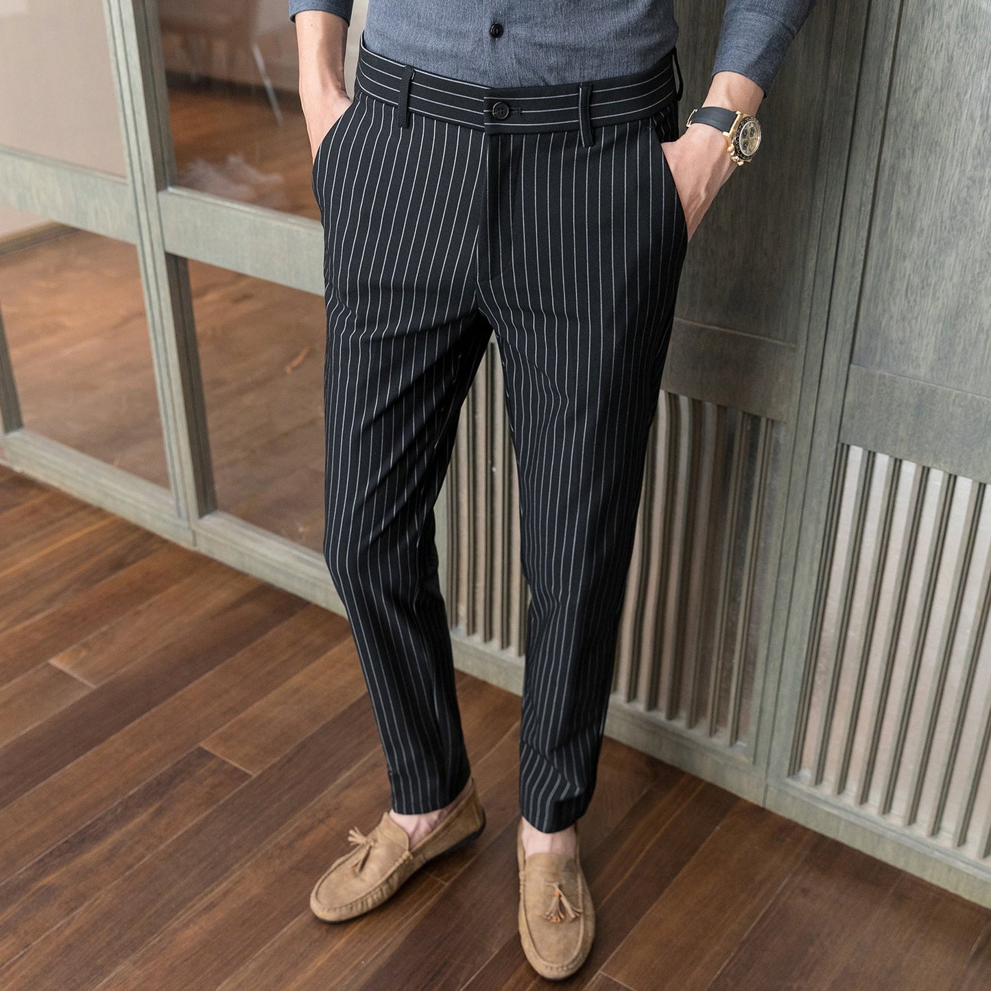 Elegante Herrenhose mit Nadelstreifen, kombiniert mit braunen Mokassins auf Holzboden. Stilvolle Business-Mode für Männer.