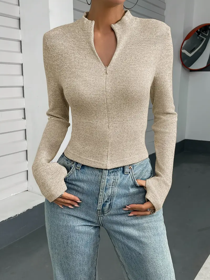 Frau trägt beige, langärmligen Strickpullover mit Reißverschluss und blaue Jeans. Modetrend, lässiger Stil, Herbstmode, Damenbekleidung.