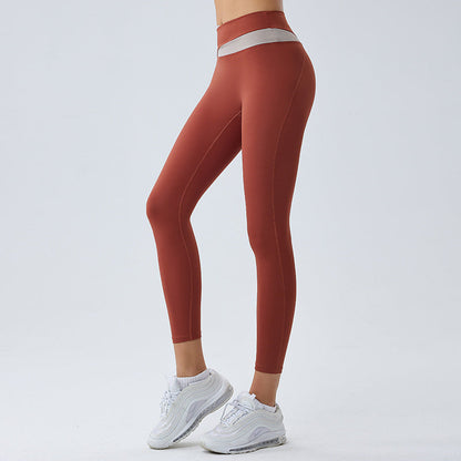 Frau in roten Leggings und weißen Sneakers, seitlich stehend. Sportbekleidung, Fitnessmode, bequeme Leggings, athletischer Look.