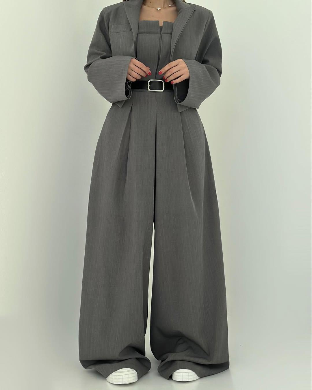 Grauer Damenanzug mit weitem Schnitt, bestehend aus Blazer und Hose, kombiniert mit weißem Sneaker. Elegante, moderne Damenmode.