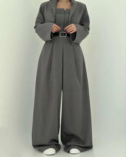 Grauer Damenanzug mit weitem Schnitt, bestehend aus Blazer und Hose, kombiniert mit weißem Sneaker. Elegante, moderne Damenmode.