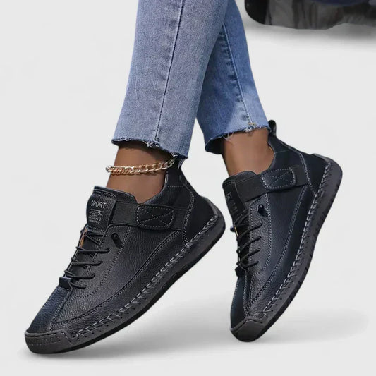 Damen Sneaker in Schwarz, lässig und modern, kombiniert mit blauen Jeans. Bequeme Freizeitschuhe, ideal für Alltag und Sport.