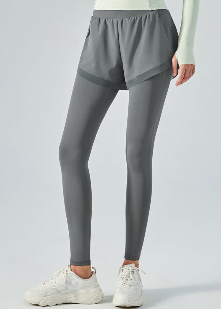 Damen-Sportleggings mit grauen Shorts, kombiniert mit weißen Sneakers. Ideal für Fitness, Yoga und Laufen. Bequeme und stilvolle Sportbekleidung.