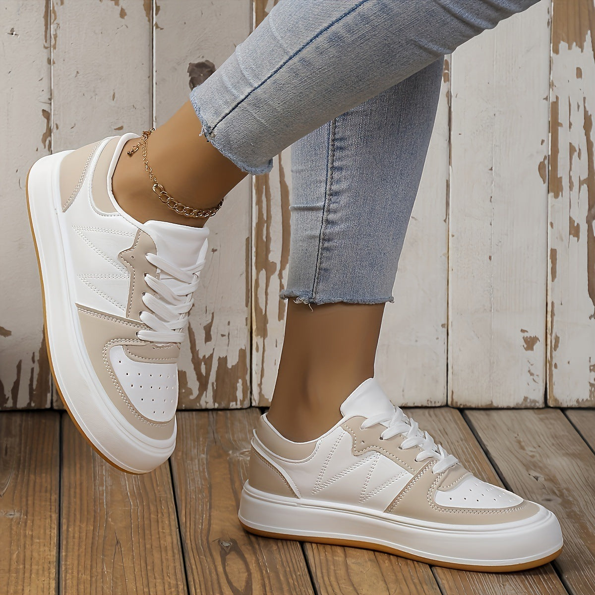 Damen-Sneaker in Beige und Weiß, getragen mit hellblauen Jeans. Modische Freizeitschuhe auf Holzboden, ideal für trendige Alltagslooks.