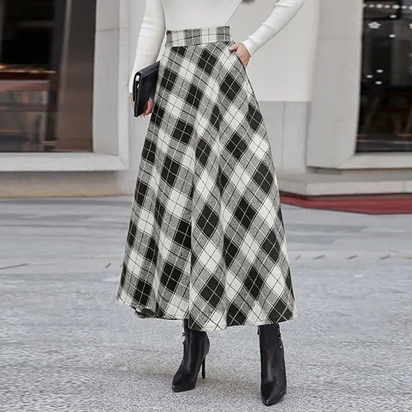 Eleganter schwarz-weiß karierter Maxirock, kombiniert mit weißen Oberteil und schwarzen Stiefeletten. Modetrend, Damenmode, stilvoller Look.