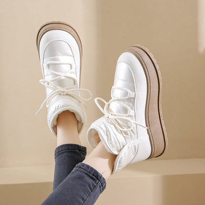 Weiße Winterstiefel mit dicker Sohle und Schnürung, getragen von Person in blauen Jeans. Modische Damenstiefel für kalte Tage.