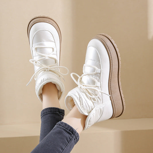 Weiße Winterstiefel mit dicker Sohle und Schnürung, getragen von Person in blauen Jeans. Modische Damenstiefel für kalte Tage.