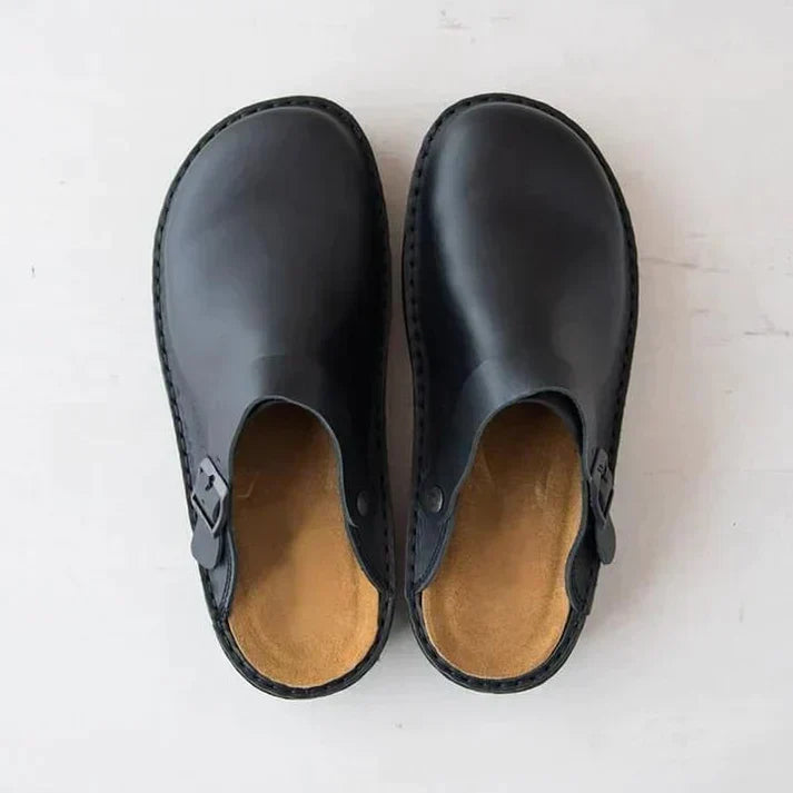 Schwarze Ledersandalen mit Schnalle, minimalistisch und modern, auf hellem Hintergrund. Bequeme Sommerschuhe für Damen und Herren.