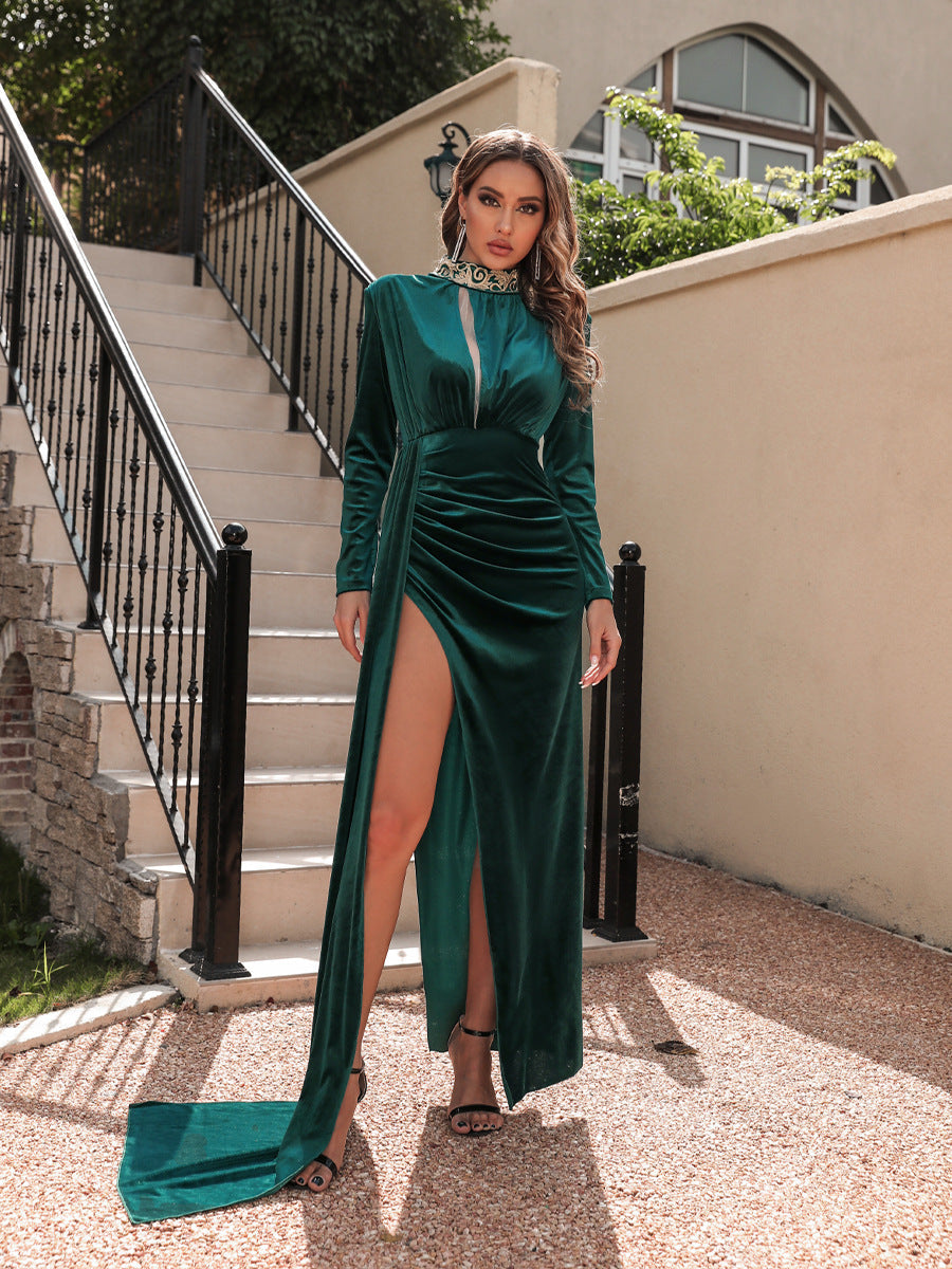 Frau in elegantem, smaragdgrünem Samtkleid mit hohem Beinschlitz, posiert vor einer Treppe. Abendmode, Glamour, stilvolle Damenbekleidung.