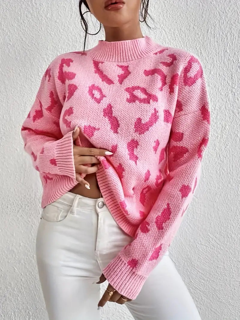 Frau in rosa Leopardenmuster-Pullover und weißen Jeans vor weißer Wand. Modetrend, Damenmode, stylischer Look, Herbstmode.