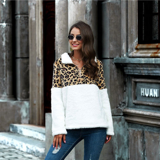 Frau in modischem Leopardenmuster-Pullover und Sonnenbrille, lächelnd vor urbaner Kulisse. Trendige Damenmode, Herbstoutfit, Streetstyle.