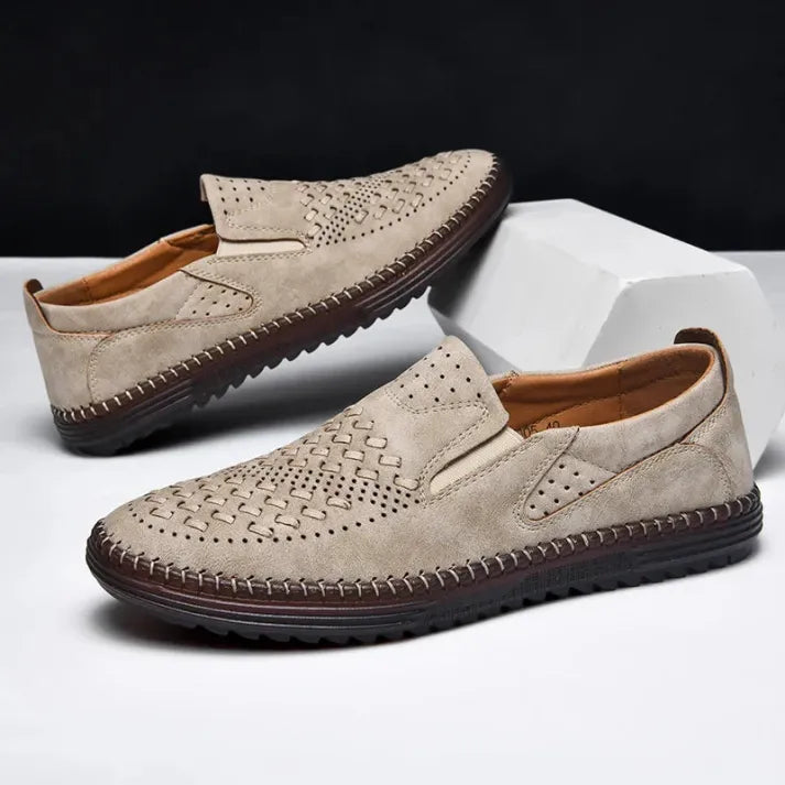 Beige Herren-Slipper aus Leder mit perforiertem Design und brauner Sohle, ideal für Sommermode und Freizeitkleidung. Elegante und bequeme Schuhe.