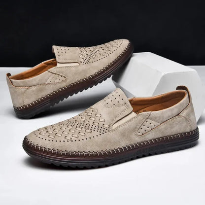 Beige Herren-Slipper aus Leder mit perforiertem Design und brauner Sohle, ideal für Sommermode und Freizeitkleidung. Elegante und bequeme Schuhe.