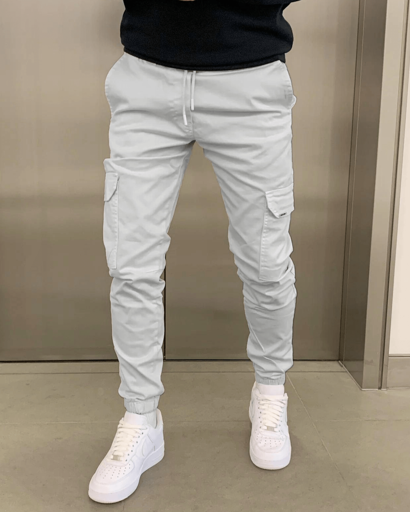 Weiße Cargo-Jogginghose mit Taschen, kombiniert mit weißen Sneakers. Moderne Herrenmode, lässiger Streetwear-Stil, ideal für Freizeit und Alltag.