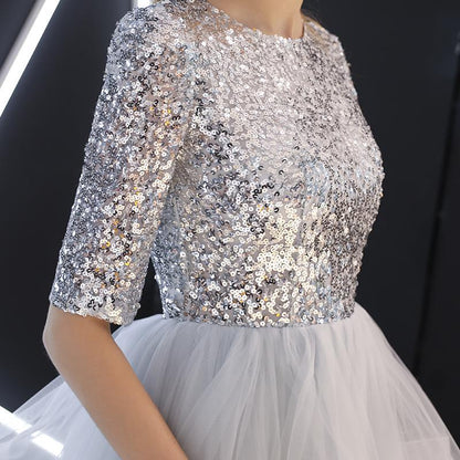 Silbernes Paillettenkleid mit halblangen Ärmeln und Tüllrock, elegantes Abendkleid, glamouröse Mode, festliche Damenbekleidung.