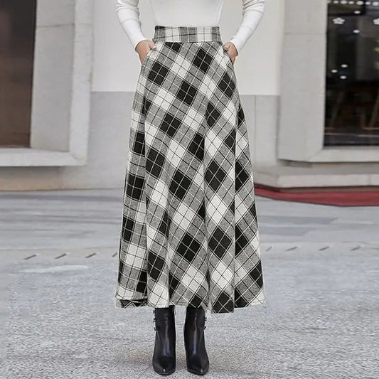 Damenmode: Langer karierter Rock in Schwarz-Weiß mit hoher Taille, kombiniert mit weißem Oberteil und schwarzen Stiefeletten. Eleganter Herbstlook.