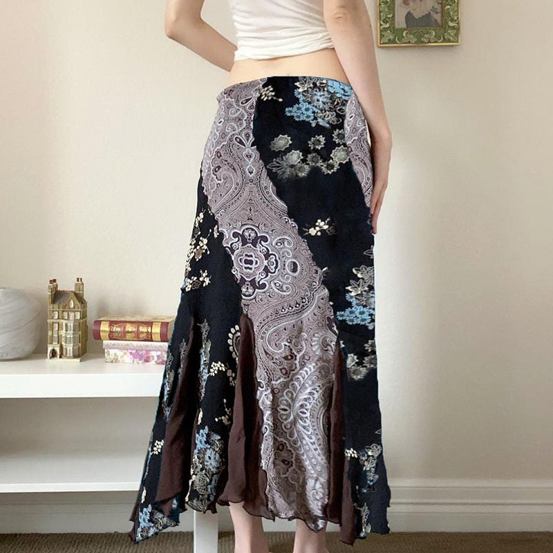 Frau trägt langen, gemusterten Rock mit Paisley- und Blumenmuster, steht in modernem Wohnzimmer. Modetrend, Damenmode, Boho-Stil.