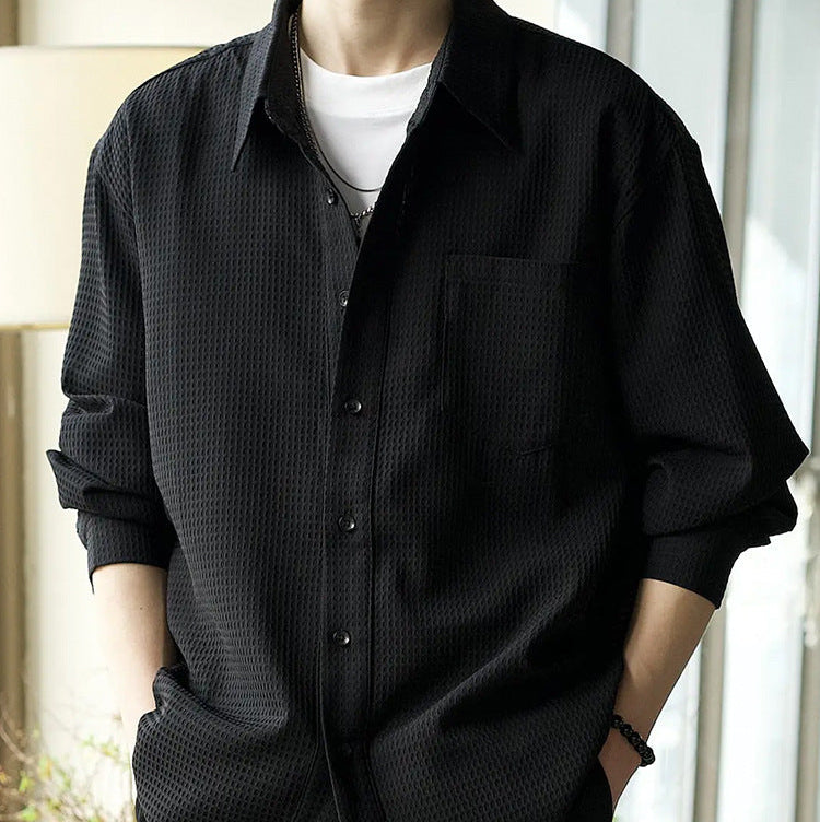 Schwarzes Herrenhemd mit Textur, lässig über weißem T-Shirt getragen. Modetrend, stilvoll, modern, ideal für Freizeit- und Alltagsoutfits.