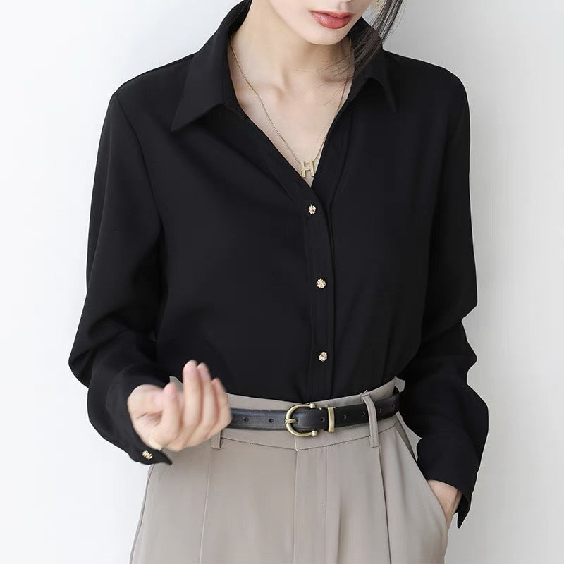 Frau in eleganter schwarzer Bluse mit goldenen Knöpfen, grauer Hose und Gürtel. Modetrend, Damenmode, stilvolle Kleidung, Business-Look.