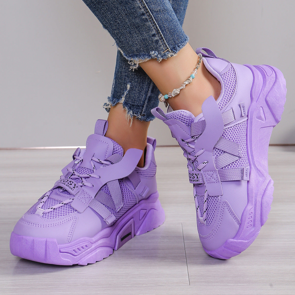 Lila Damen-Sneaker mit dicker Sohle, getragen mit Jeans. Modische Sportschuhe, trendiges Design, ideal für Freizeit und Streetwear.