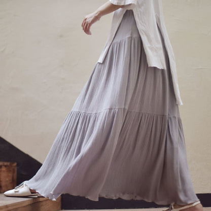 Frau in fließendem, grauem Maxirock und weißer Bluse geht eine Treppe hinunter. Modetrend, eleganter Stil, Damenmode, lässiges Outfit.