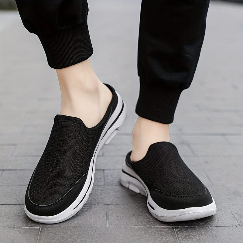 Schwarze Slip-On-Sneaker auf grauem Gehweg, bequeme Freizeitschuhe für Damen und Herren, atmungsaktives Mesh, ideal für Alltag und Sport.