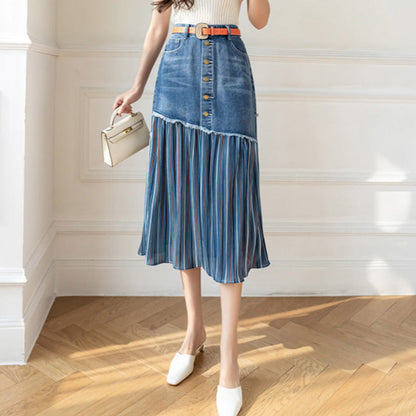 Frau in modischem Jeansrock mit Knopfleiste und Falten, trägt weiße Schuhe und eine kleine Handtasche, steht auf Holzboden vor weißer Wand.