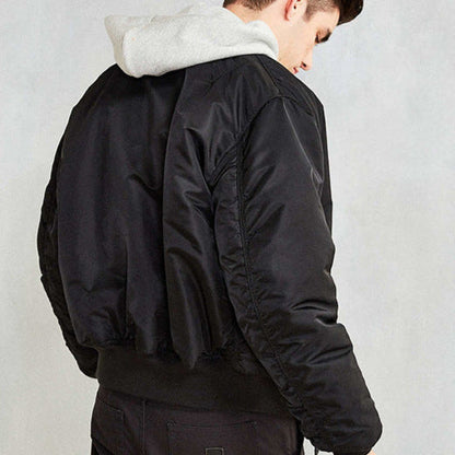 Junger Mann in schwarzer Bomberjacke und grauem Kapuzenpullover, Rückansicht. Modetrend, Streetwear, lässiger Stil, Herbstmode.