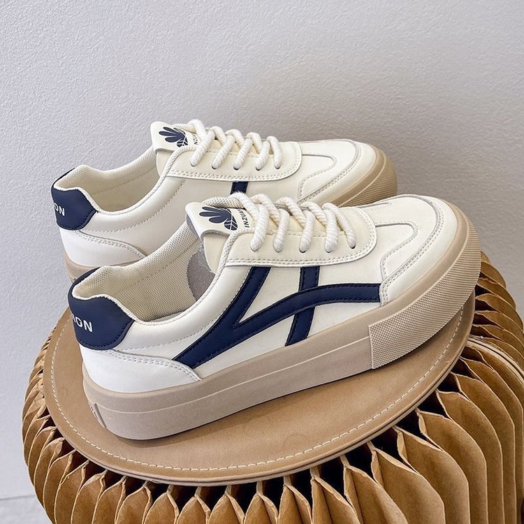 Weiße Sneaker mit blauen Details auf Wellpappe, modische Turnschuhe, bequeme Freizeitschuhe, trendige Damen- und Herrenschuhe, stilvolles Design.
