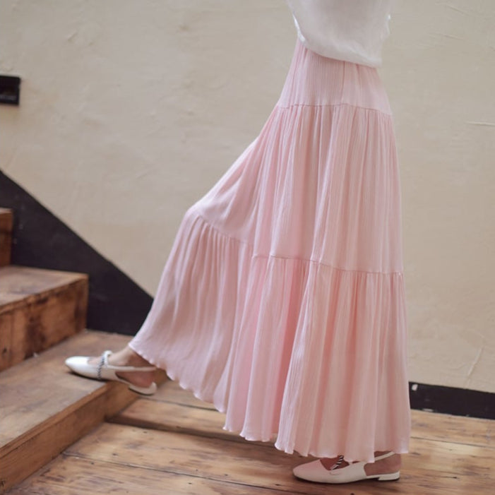 Frau in rosa Maxirock auf Holztreppe, modisch, elegant, Sommermode, fließender Stoff, feminine Kleidung, stilvoll, Freizeitlook.