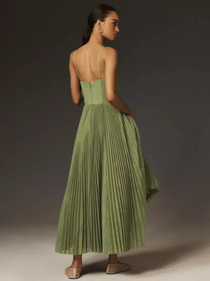 Frau in langem, grünem, plissiertem Kleid mit Spaghettiträgern, seitlich stehend, elegantes Abendoutfit, modische Damenmode, stilvolle Kleidung.