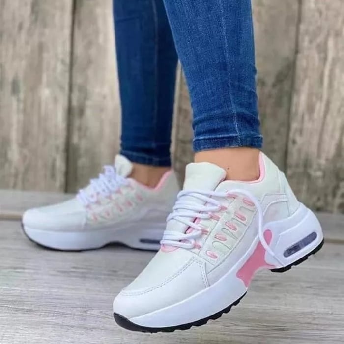 Weiße Damen-Sneaker mit rosa Akzenten, getragen von Person in blauen Jeans. Modische Sportschuhe, ideal für Freizeit und Sport.