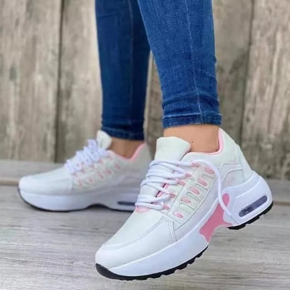Weiße Damen-Sneaker mit rosa Akzenten, getragen von Person in blauen Jeans. Modische Sportschuhe, ideal für Freizeit und Sport.