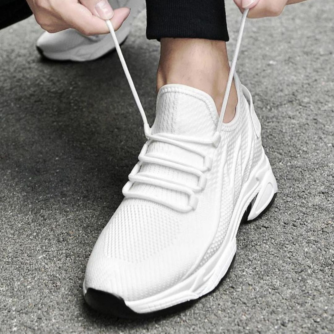 Weiße Sportschuhe mit Schnürsenkeln auf grauem Asphalt, moderne Sneaker-Designs, bequeme Laufschuhe, atmungsaktives Material, sportliche Mode.