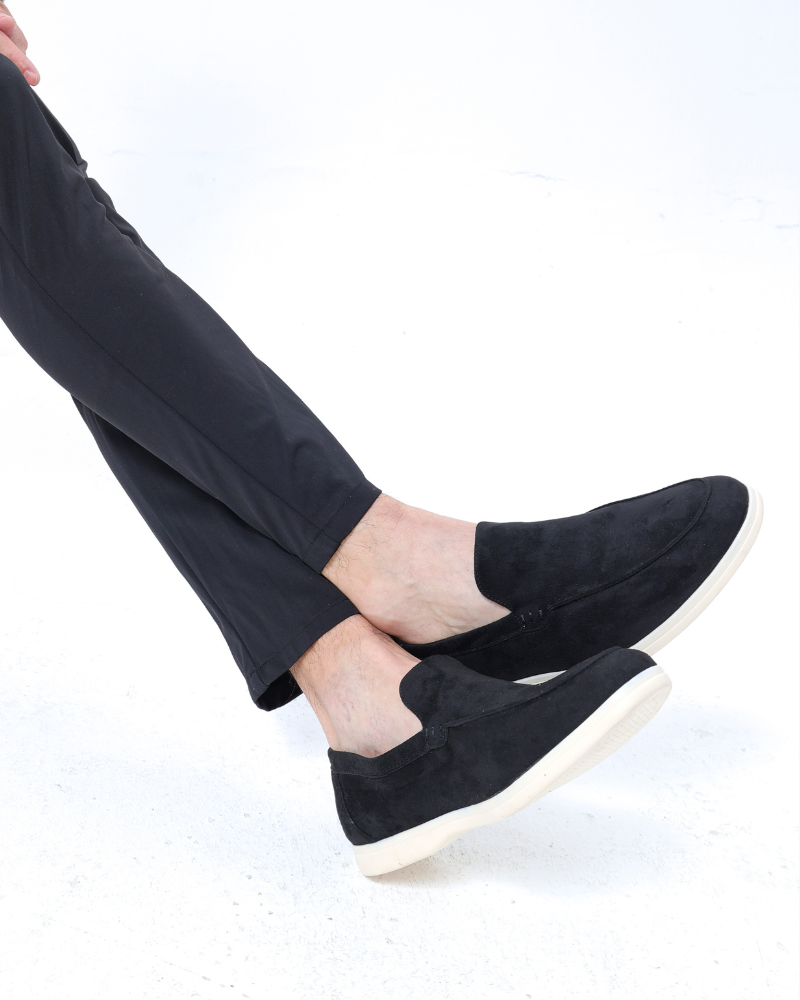 Schwarze Wildleder-Slipper für Herren, kombiniert mit eleganten, dunklen Hosen. Stilvolle, bequeme Herrenschuhe für Freizeit und Büro.
