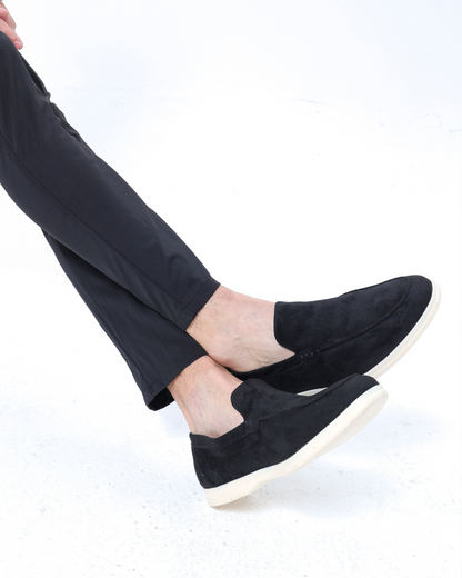 Schwarze Wildleder-Slipper für Herren, kombiniert mit eleganten, dunklen Hosen. Stilvolle, bequeme Herrenschuhe für Freizeit und Büro.