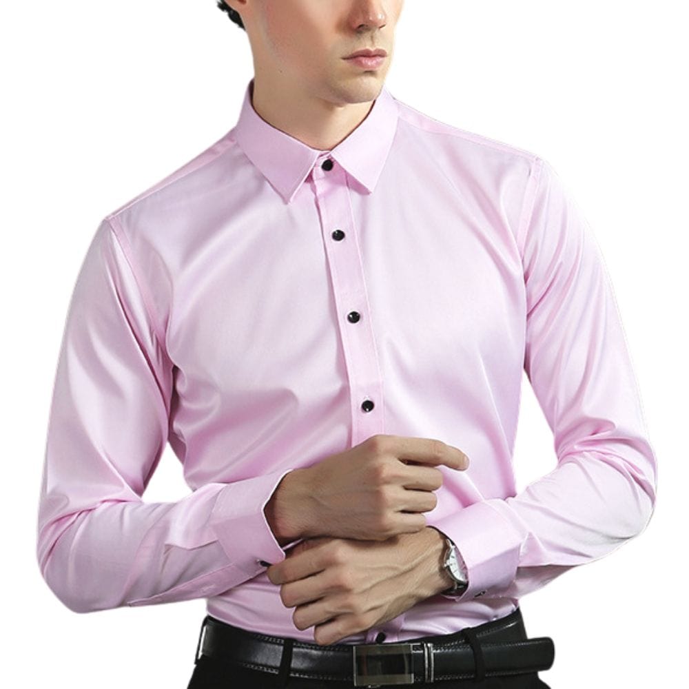 Mann in rosa Hemd mit schwarzen Knöpfen, formell gekleidet, trägt eine Uhr, vor weißem Hintergrund. Elegantes Herrenhemd, Businessmode.