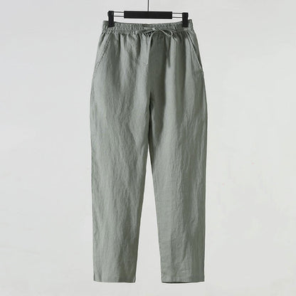Graue Leinenhose mit elastischem Bund und Kordelzug, lässiger Stil, ideal für Sommermode, komfortabel und atmungsaktiv, auf weißem Hintergrund.