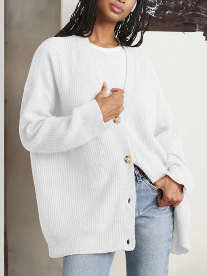 Frau trägt weißen Strick-Cardigan mit Holzknöpfen, kombiniert mit blauer Jeans. Modetrend, lässiger Stil, Damenmode, Herbstoutfit.