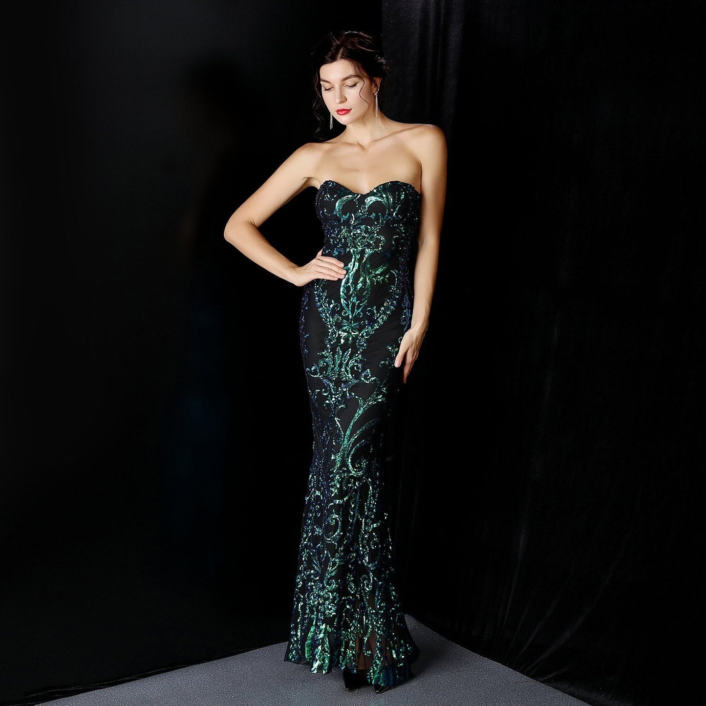 Frau in elegantem, schulterfreiem Abendkleid mit grünem Muster vor schwarzem Hintergrund. Perfekt für Gala, Ball oder Abendveranstaltung.