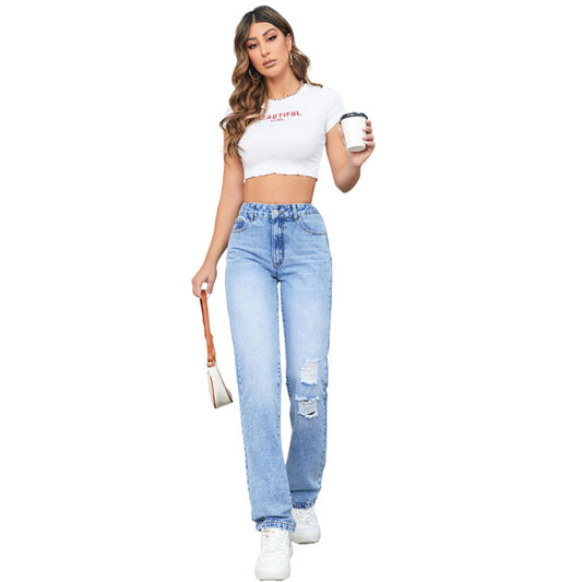 Junge Frau in zerrissenen Jeans und weißem Crop-Top, hält Kaffeebecher und Handtasche. Modetrend, Freizeitlook, Streetstyle.