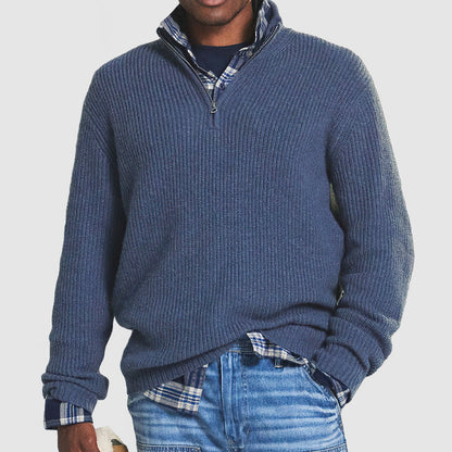 Mann in blauem Strickpullover mit Reißverschluss, kariertem Hemd und Jeans. Modischer Freizeitlook für Herren.