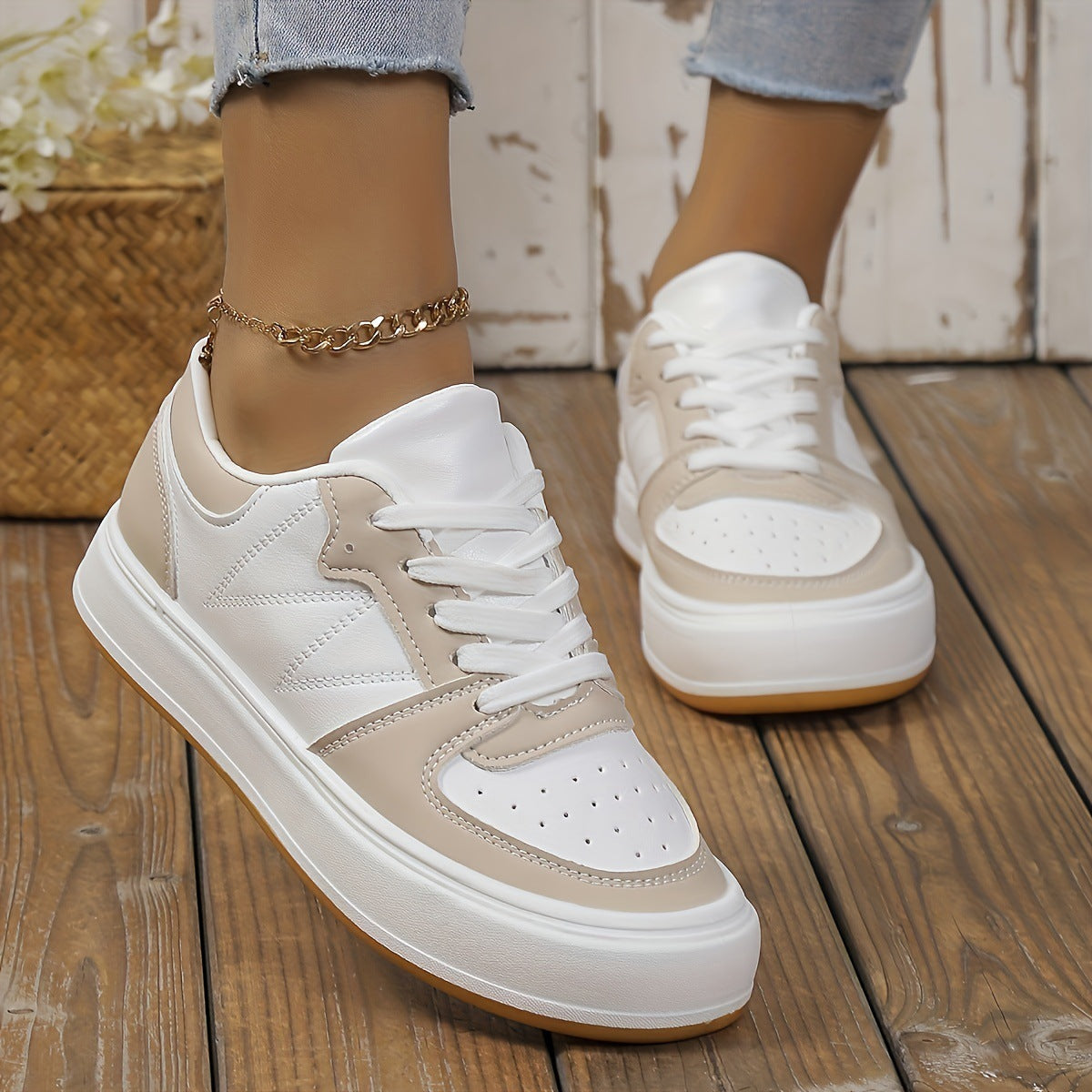 Damen-Sneaker in Beige und Weiß auf Holzboden, getragen mit Jeans. Modische Freizeitschuhe, ideal für Alltag und Streetwear.