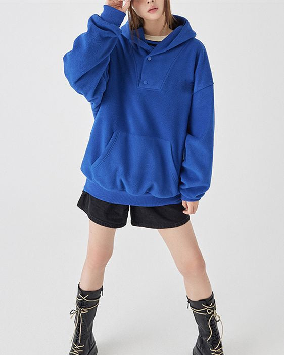 Frau in blauem Hoodie und schwarzen Shorts, trägt schwarze Stiefel. Modetrend, lässiger Stil, bequeme Freizeitkleidung.