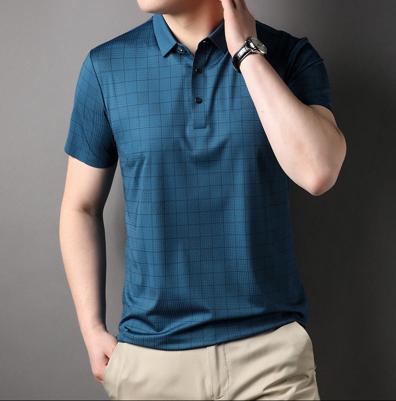 Mann trägt blaues kariertes Polohemd und beige Hose, Hand am Kragen, Armbanduhr sichtbar. Elegante Freizeitmode für Herren.
