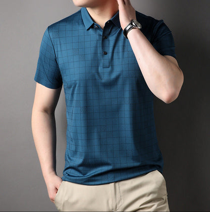 Mann trägt blaues kariertes Polohemd und beige Hose, Hand am Kragen, Armbanduhr sichtbar. Elegante Freizeitmode für Herren.