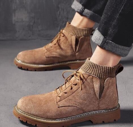 Braune Herren-Winterstiefel aus Wildleder mit dicker Sohle und Schnürung, kombiniert mit hochgekrempelten Jeans. Ideal für kaltes Wetter.