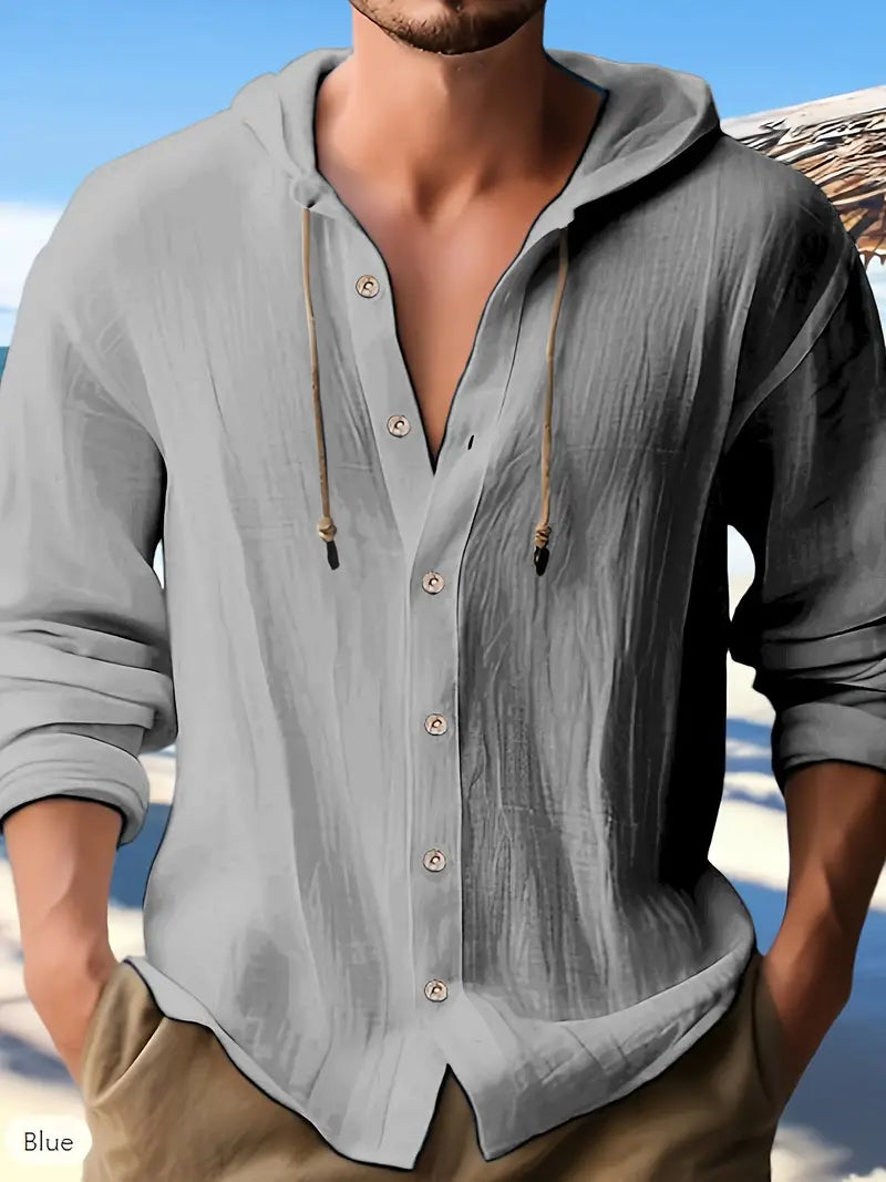 Mann in grauem Leinenhemd mit Kapuze und Knopfleiste am Strand. Sommermode, lässiger Stil, Herrenbekleidung.